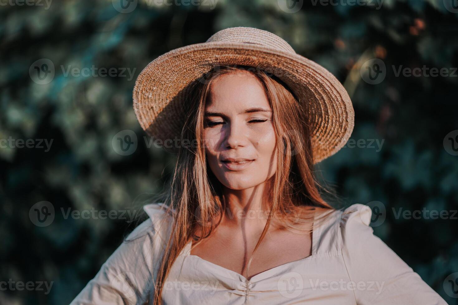 Woman with straw hat stands in front of vineyard. She is wearing a light dress and posing for a photo. Travel concept to different countries photo