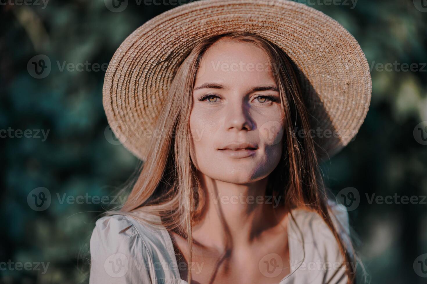 Woman with straw hat stands in front of vineyard. She is wearing a light dress and posing for a photo. Travel concept to different countries photo