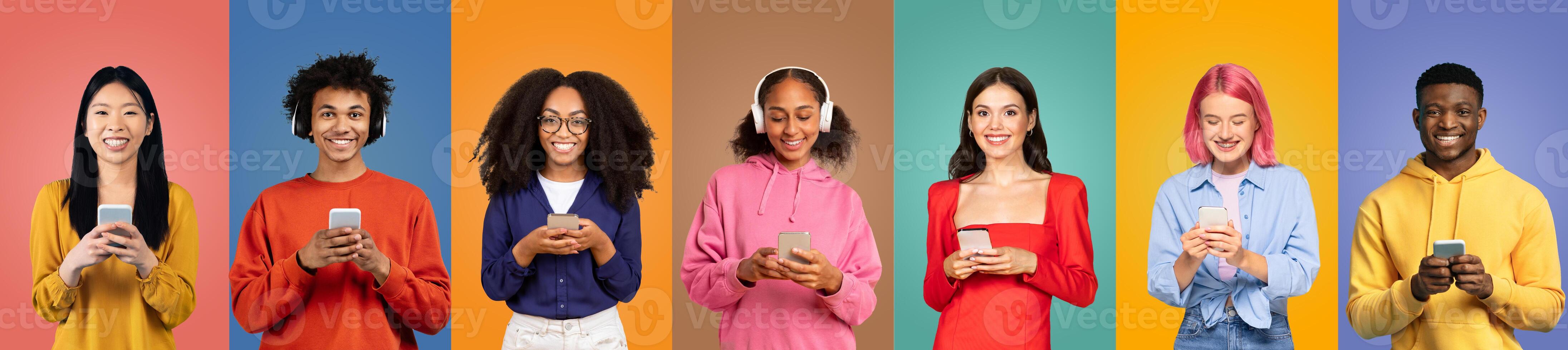 A group of seven young people stands in a row, each engaged with their smartphones. They are surrounded by vibrant, solid-colored backgrounds that enhance their cheerful expressions and style. photo
