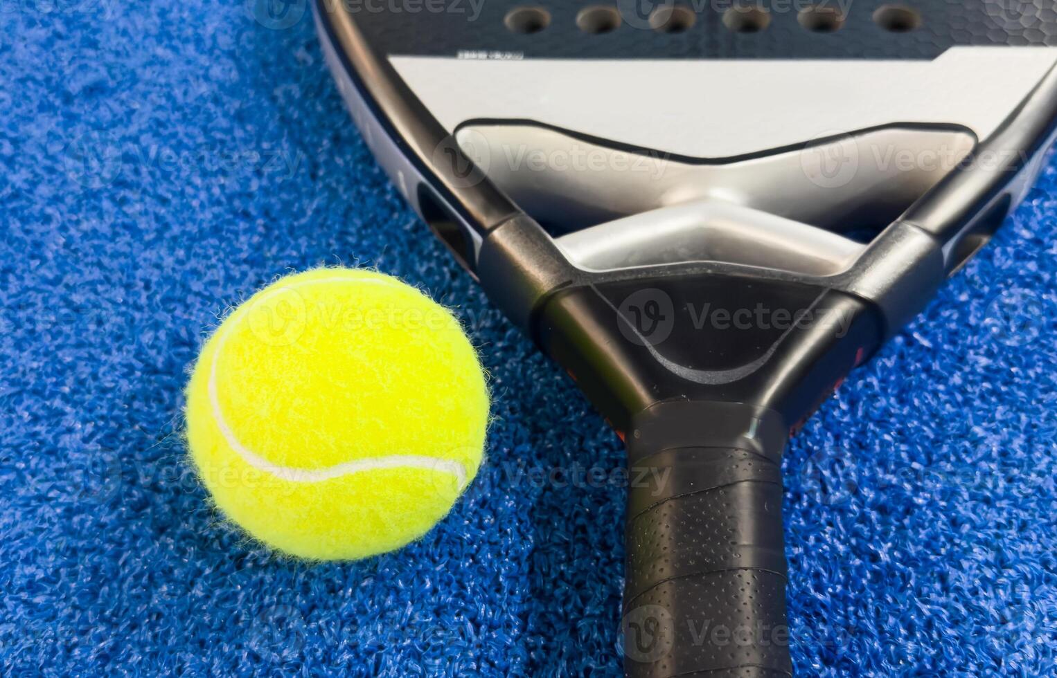 Paddle racket with a ball ready to play the fastest growing sport in recent years worldwide. Padel court in summer, the perfect time to practice this sporting discipline and release stress. photo