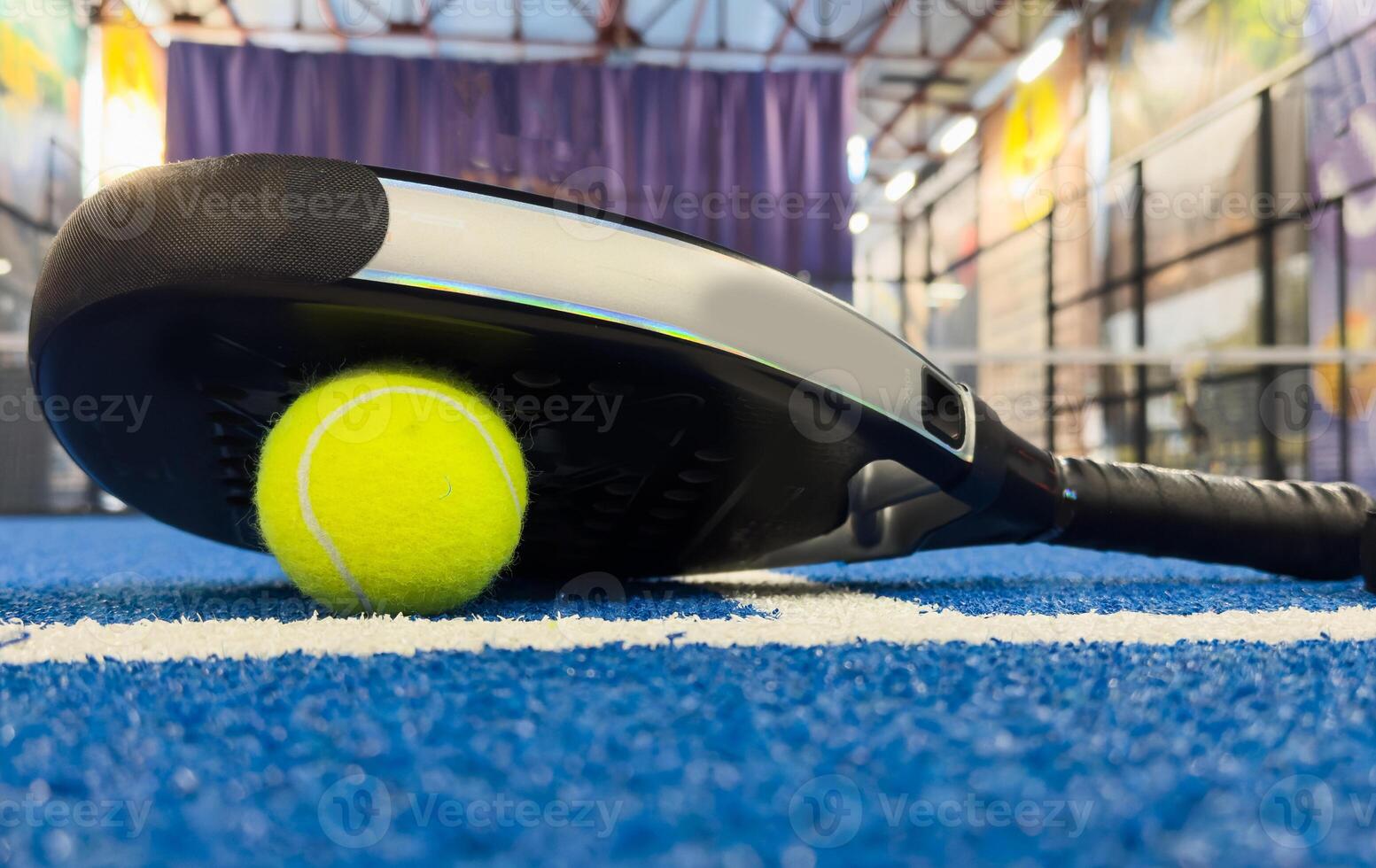 Paddle racket with a ball ready to play the fastest growing sport in recent years worldwide. Padel court in summer, the perfect time to practice this sporting discipline and release stress. photo