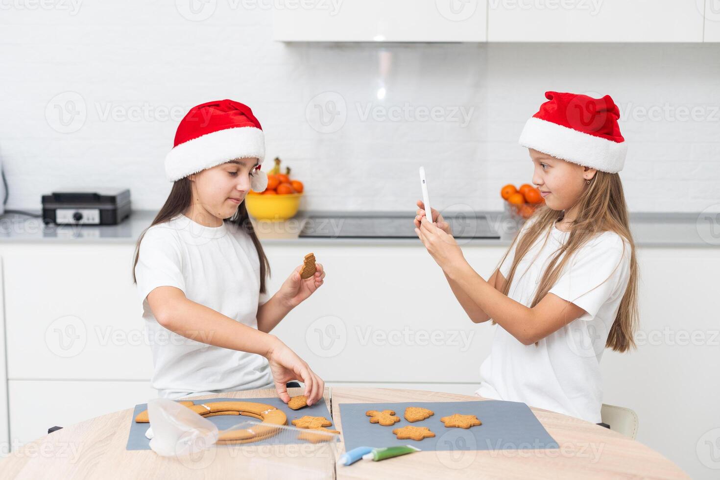 Two girls sisters are playing around in the kitchen after making Christmas cookies, they draw with flour on the table and on their faces. Christmas, New Year concept photo