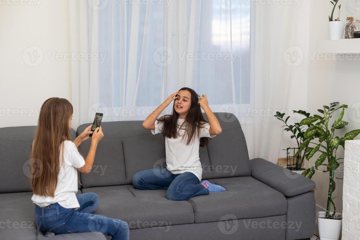 Child with smartphone at home. Two kids using smart phone, surfing internet or using social media. Two kids using online mobile phone, call, watching content, playing games, sitting on couch photo