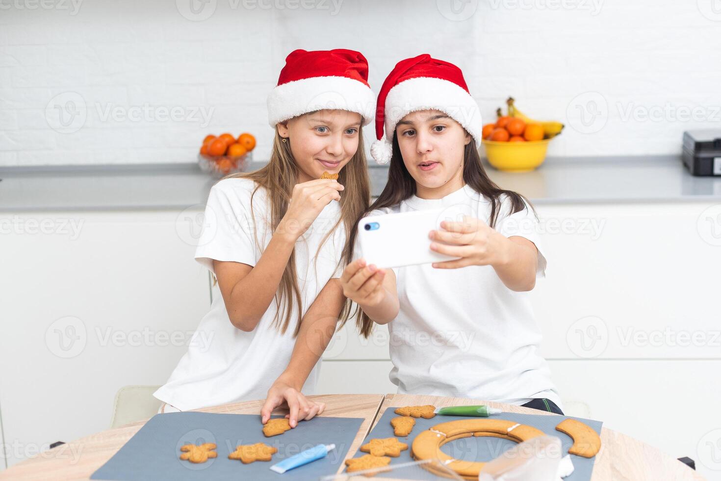 Two girls sisters are playing around in the kitchen after making Christmas cookies, they draw with flour on the table and on their faces. Christmas, New Year concept photo