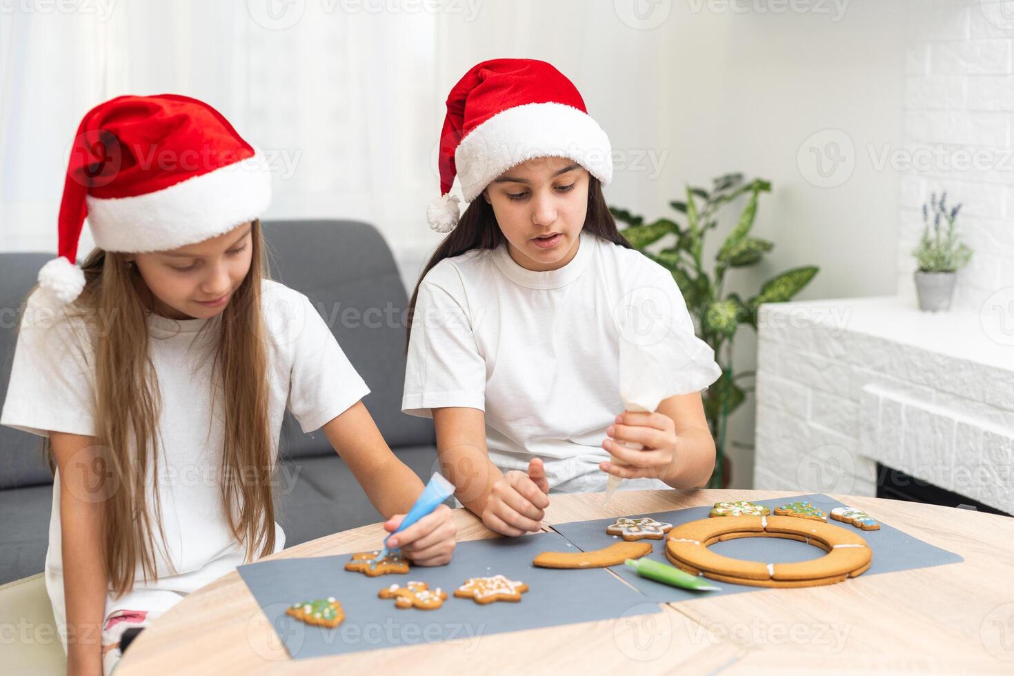 Two girls sisters are playing around in the kitchen after making Christmas cookies, they draw with flour on the table and on their faces. Christmas, New Year concept photo