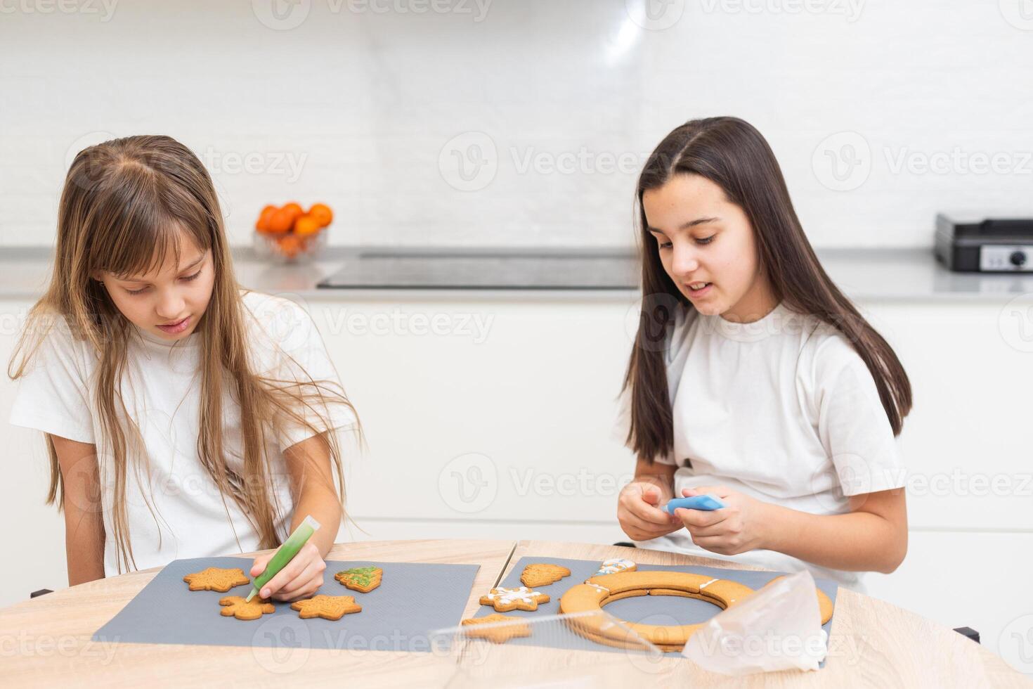 Two girls sisters are playing around in the kitchen after making Christmas cookies, they draw with flour on the table and on their faces. Christmas, New Year concept photo