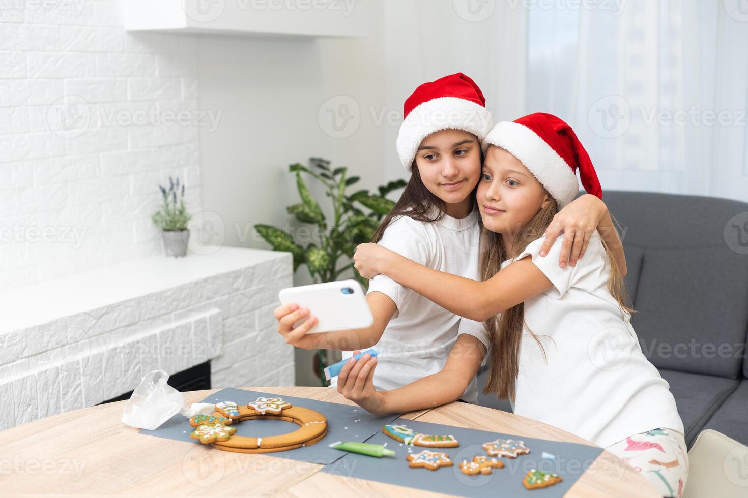 Two girls sisters are playing around in the kitchen after making Christmas cookies, they draw with flour on the table and on their faces. Christmas, New Year concept photo