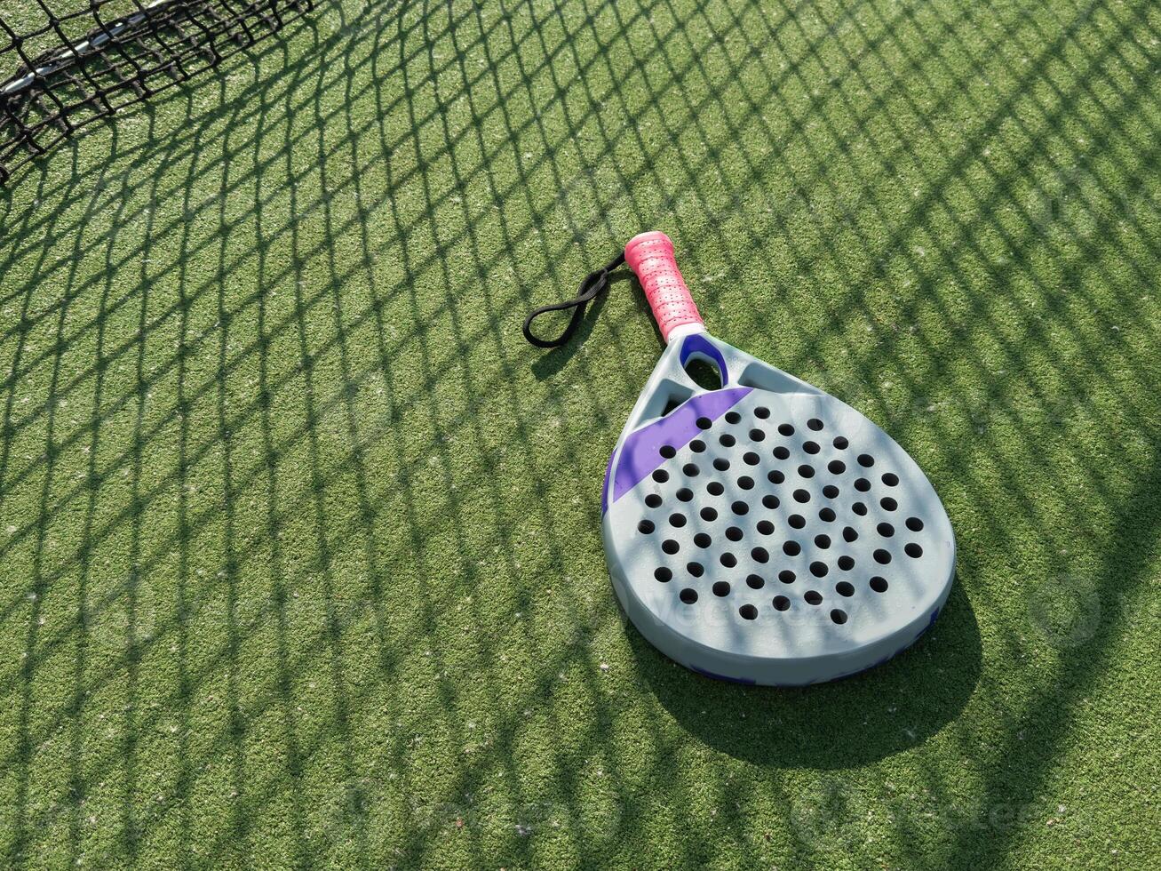 Paddle tennis racket, ball and net on the grass photo