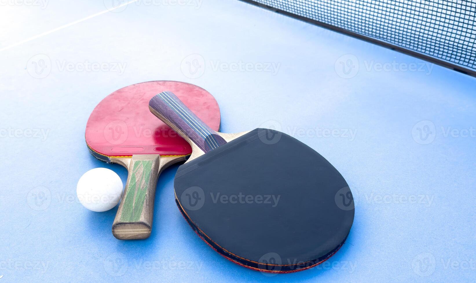 wooden rackets for playing table tennis and a net on a blue background, top view photo