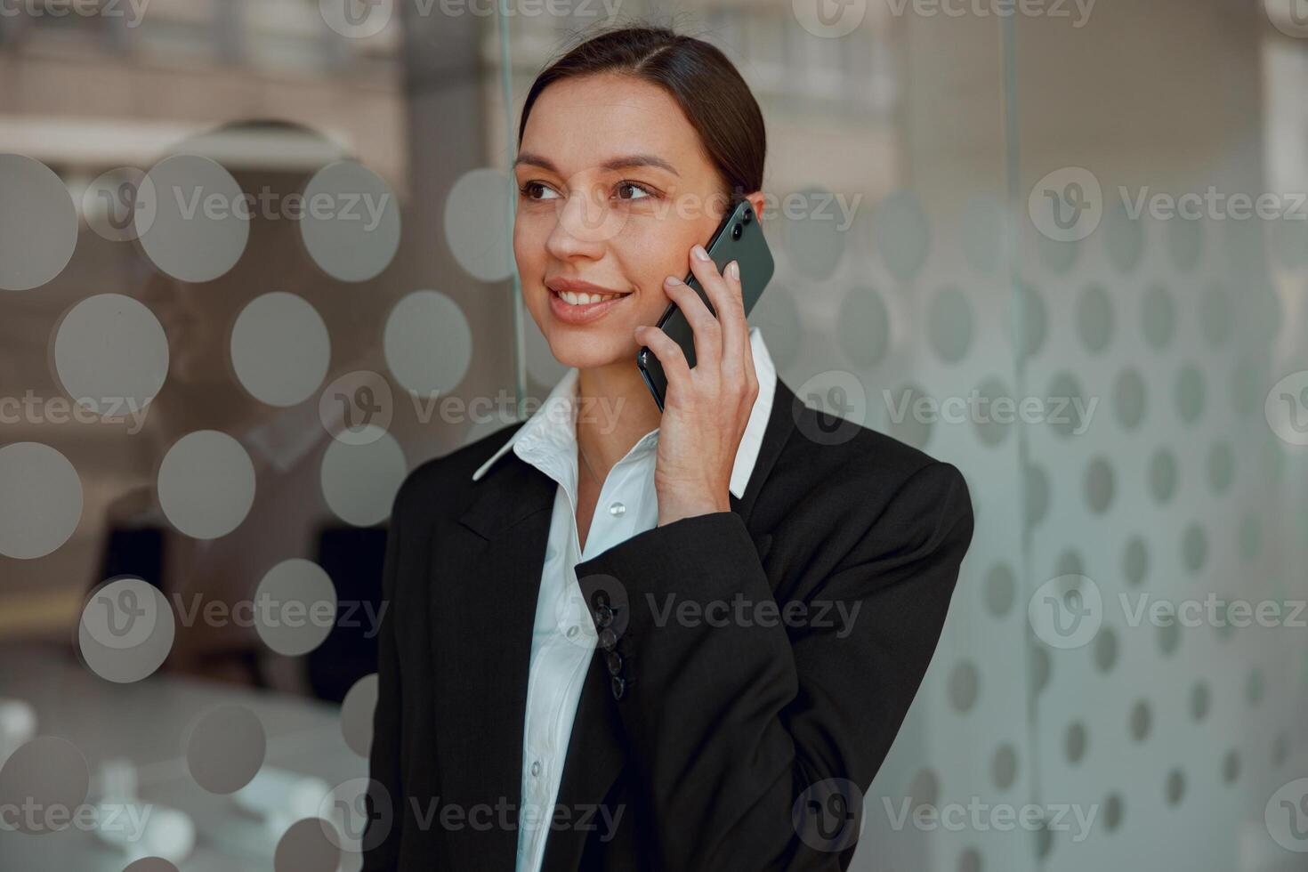 Businesswoman in formal attire talking on the phone at a modern office environment photo