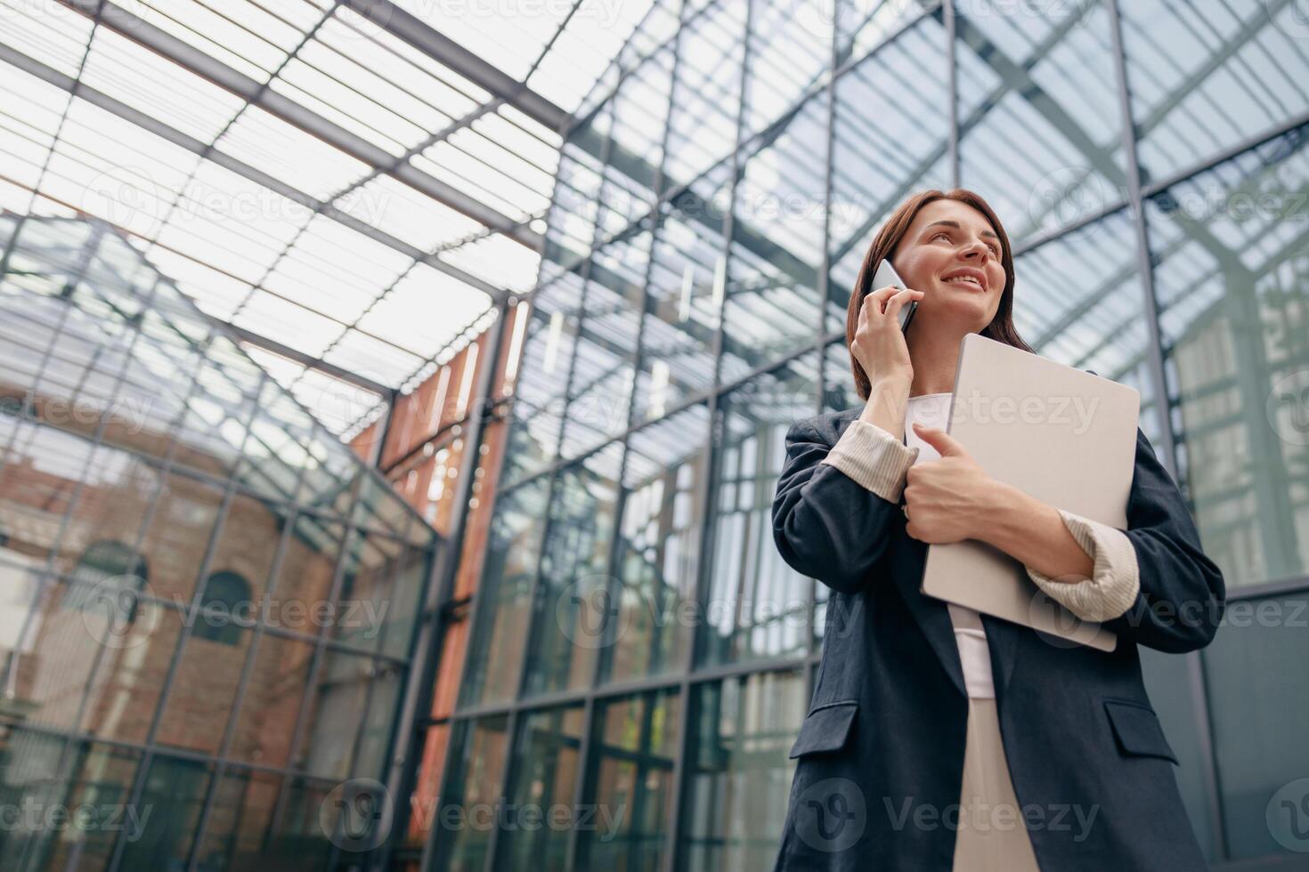 Confident Businesswoman talking on the phone while holding documents in a modern office setting photo