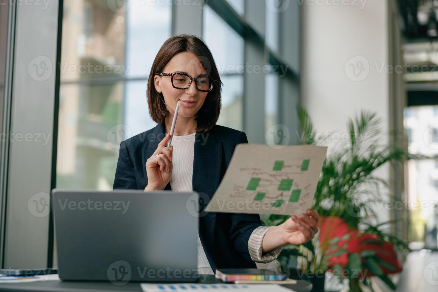A successful businesswoman is focused on analyzing data reports in a modern office environment photo