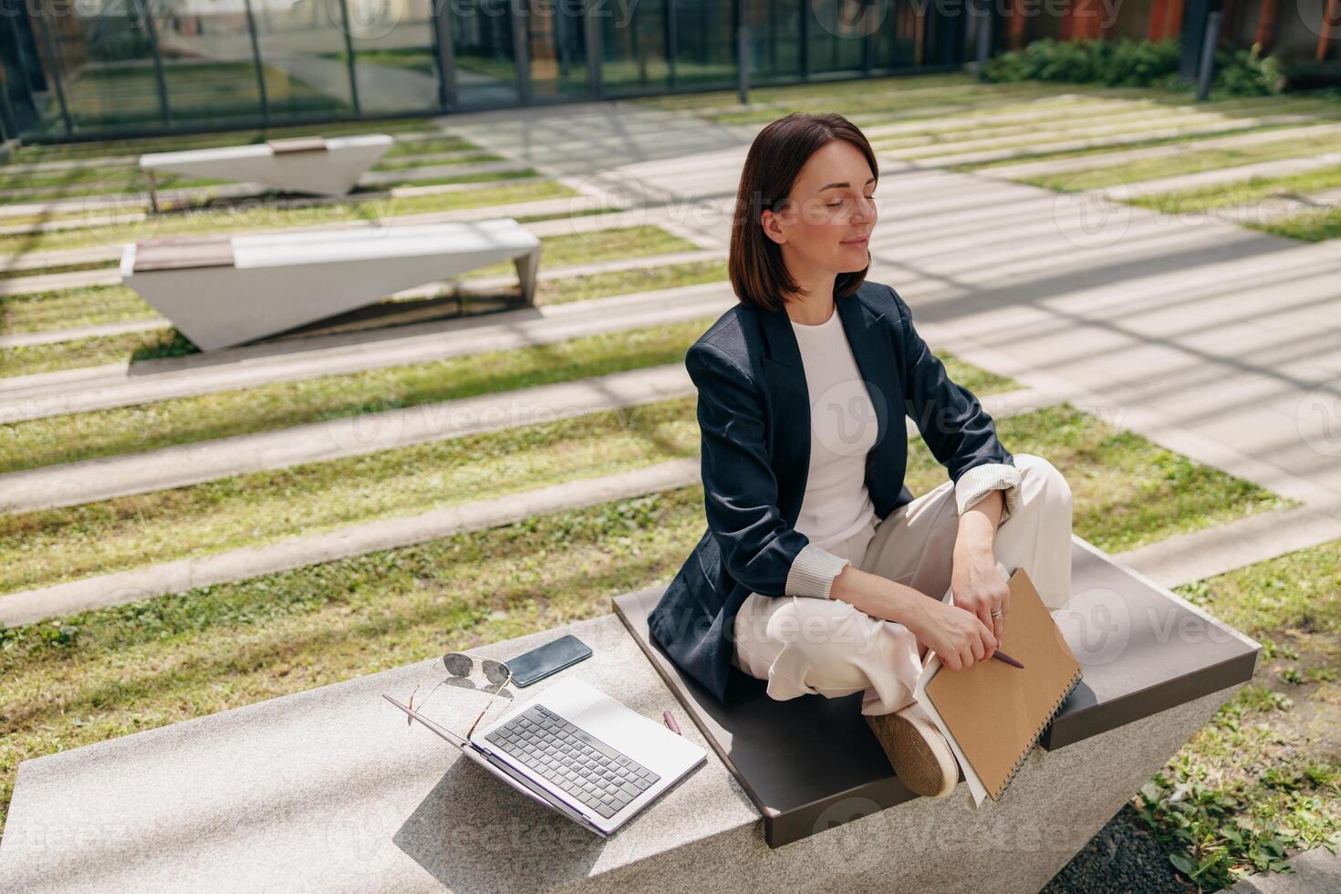 A businesswoman finds serenity in nature while working on her laptop and notebook photo