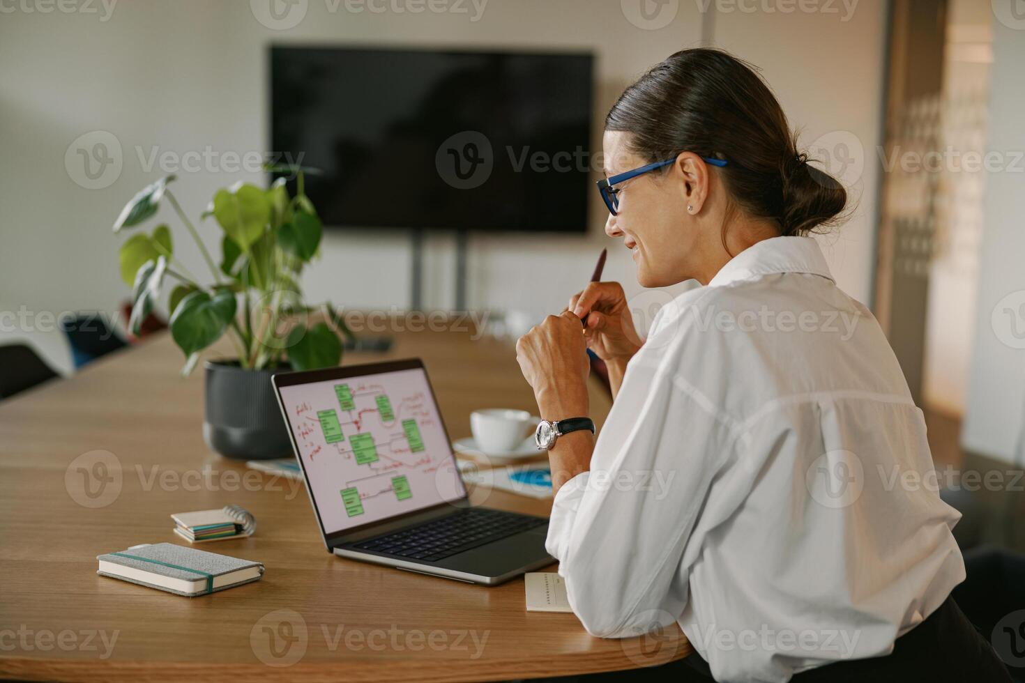 A woman is diligently working creatively on her laptop within a modern office environment photo
