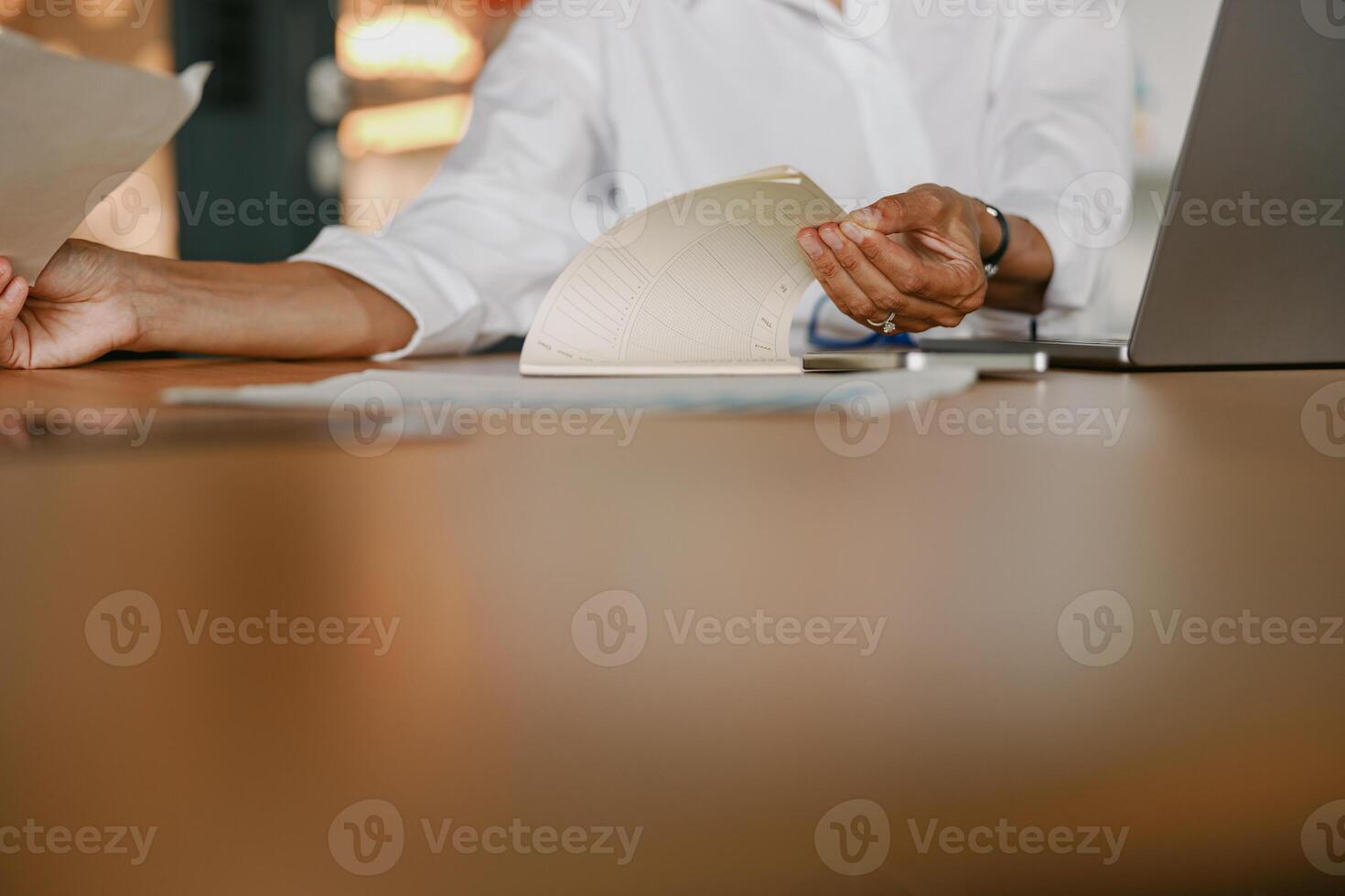 A neat and organized workspace featuring documents, papers, and a laptop placed on the table photo