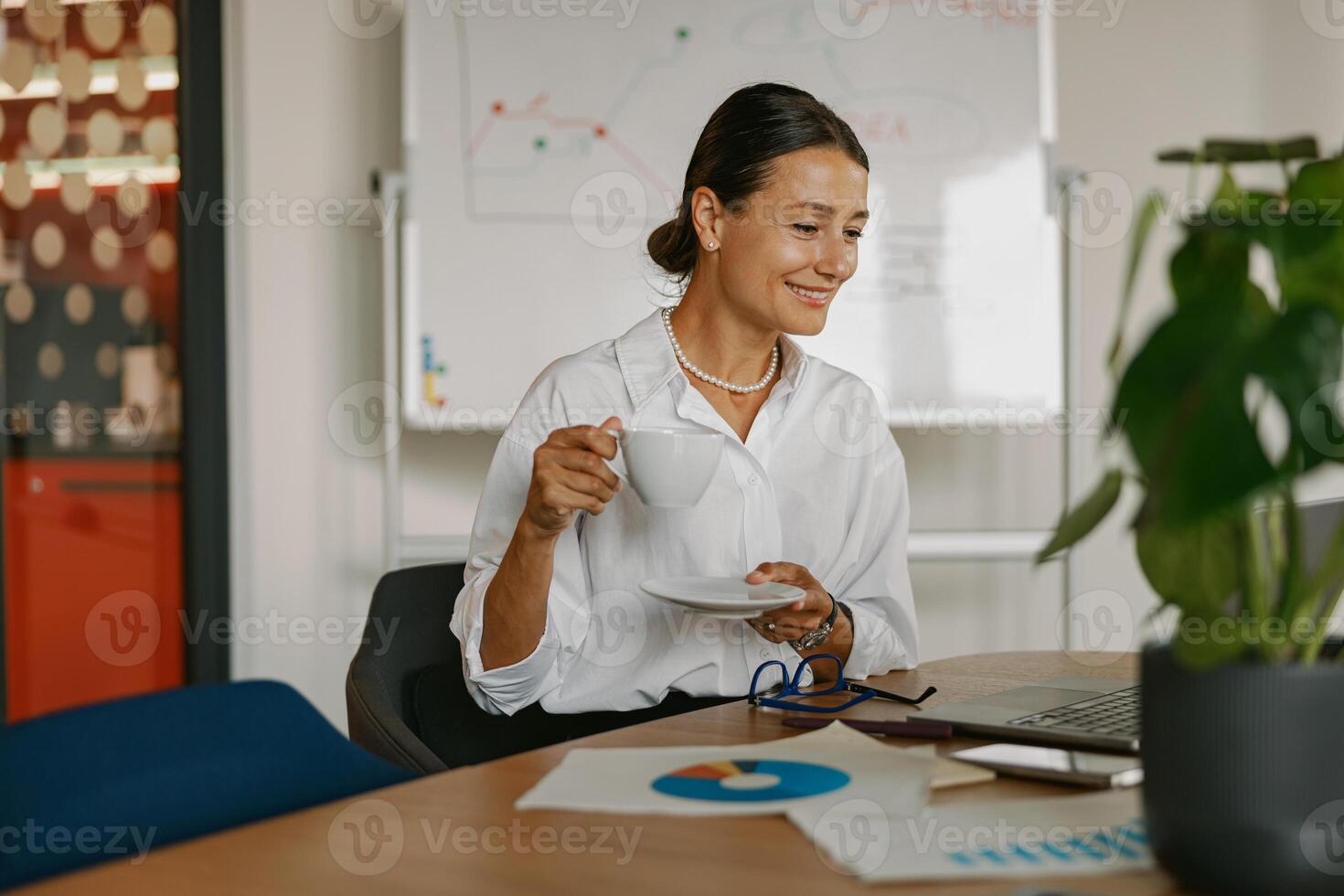 A Professional Woman is Enjoying a Cup of Coffee While in a Modern Office Setting Today photo