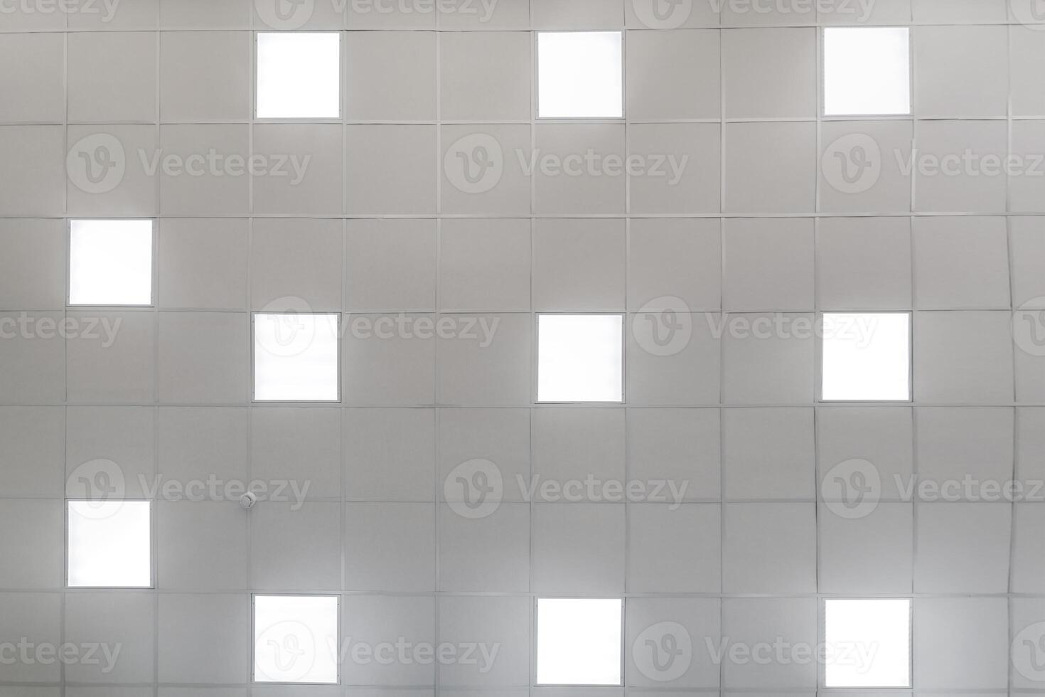 cassette stretched or suspended ceiling with square halogen spots lamps and drywall construction in empty room in house or office. Looking up view photo