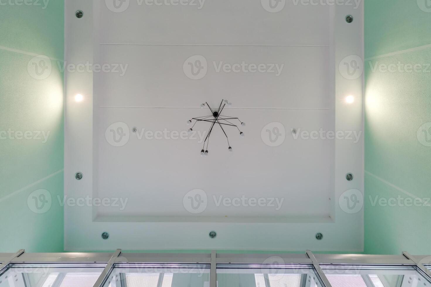suspended ceiling with halogen spots lamps and drywall construction in empty room in apartment or house. Stretch ceiling white and complex shape. photo