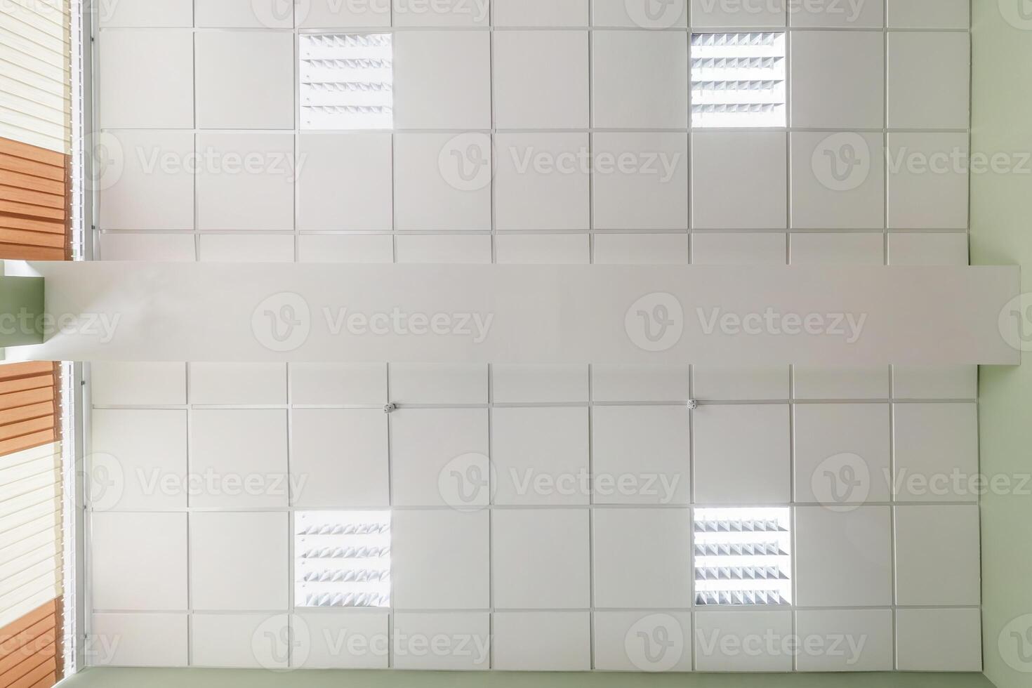 cassette stretched or suspended ceiling with square halogen spots lamps and drywall construction in empty room in house or office. Looking up view photo