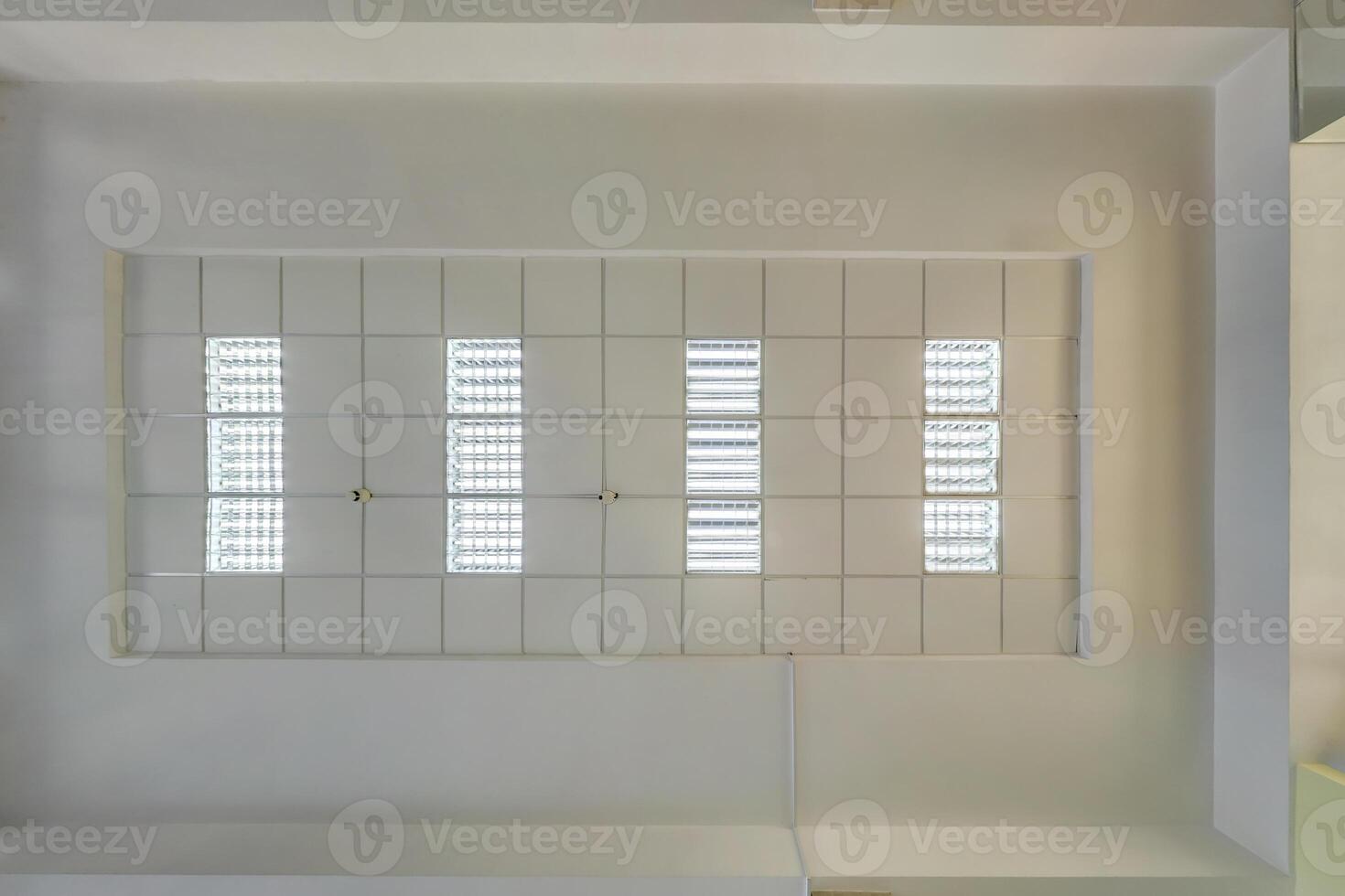 cassette stretched or suspended ceiling with square halogen spots lamps and drywall construction in empty room in house or office. Looking up view photo