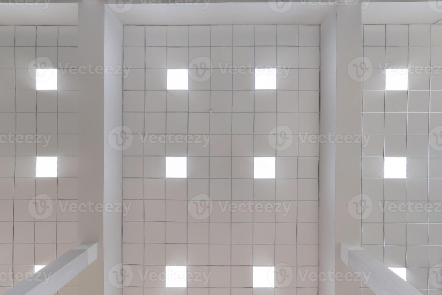 cassette stretched or suspended ceiling with square halogen spots lamps and drywall construction in empty room in house or office. Looking up view photo