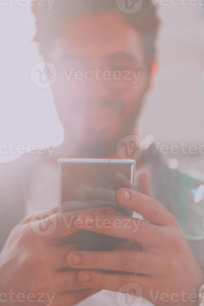 A young man utilizes his smartphone outdoors, showcasing the seamless integration of technology and mobility in modern professional life. photo