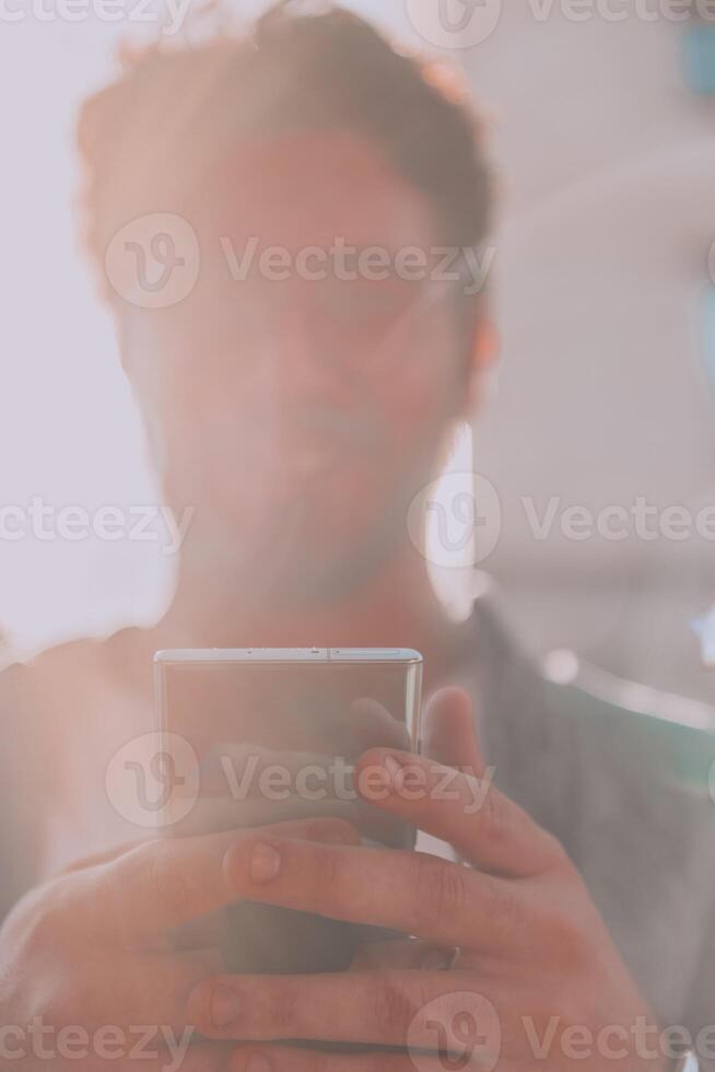A young man utilizes his smartphone outdoors, showcasing the seamless integration of technology and mobility in modern professional life. photo