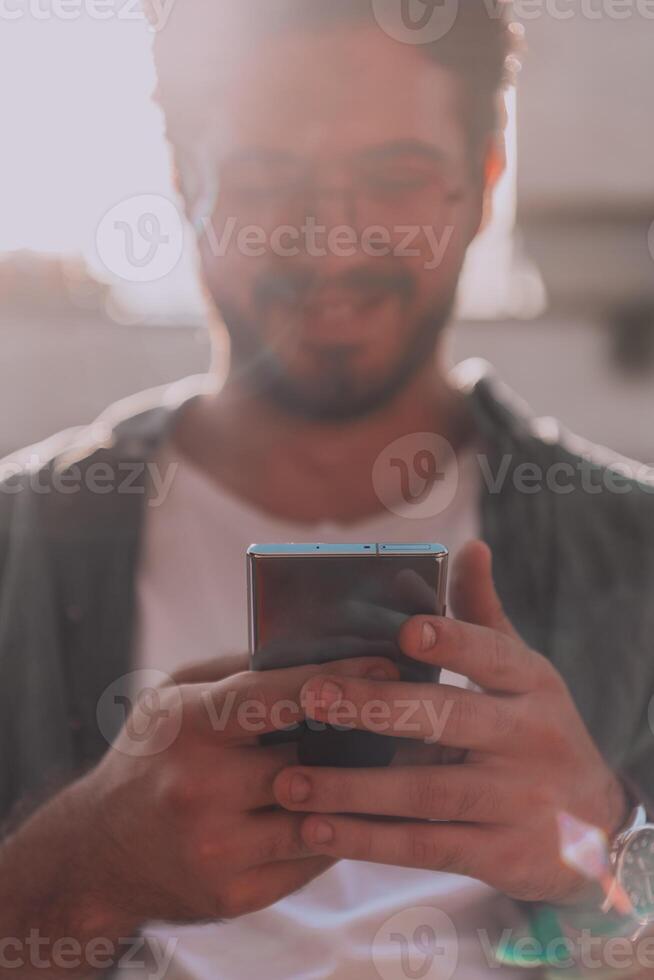 A young man utilizes his smartphone outdoors, showcasing the seamless integration of technology and mobility in modern professional life. photo
