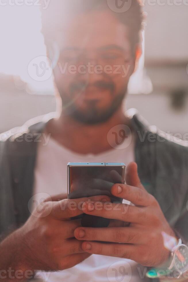 A young man utilizes his smartphone outdoors, showcasing the seamless integration of technology and mobility in modern professional life. photo