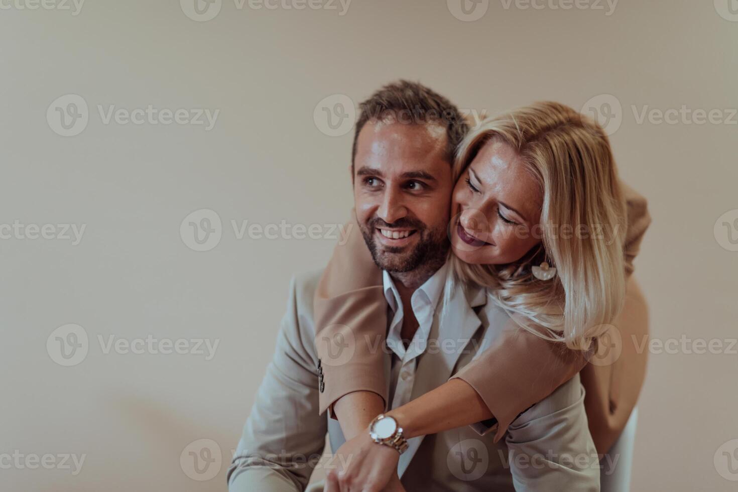 A business couple posing for a photograph together against a beige backdrop, capturing their professional partnership and creating a timeless image of unity and success. photo