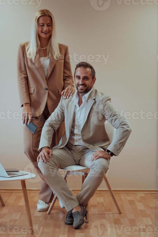 A business couple posing for a photograph together against a beige backdrop, capturing their professional partnership and creating a timeless image of unity and success. photo