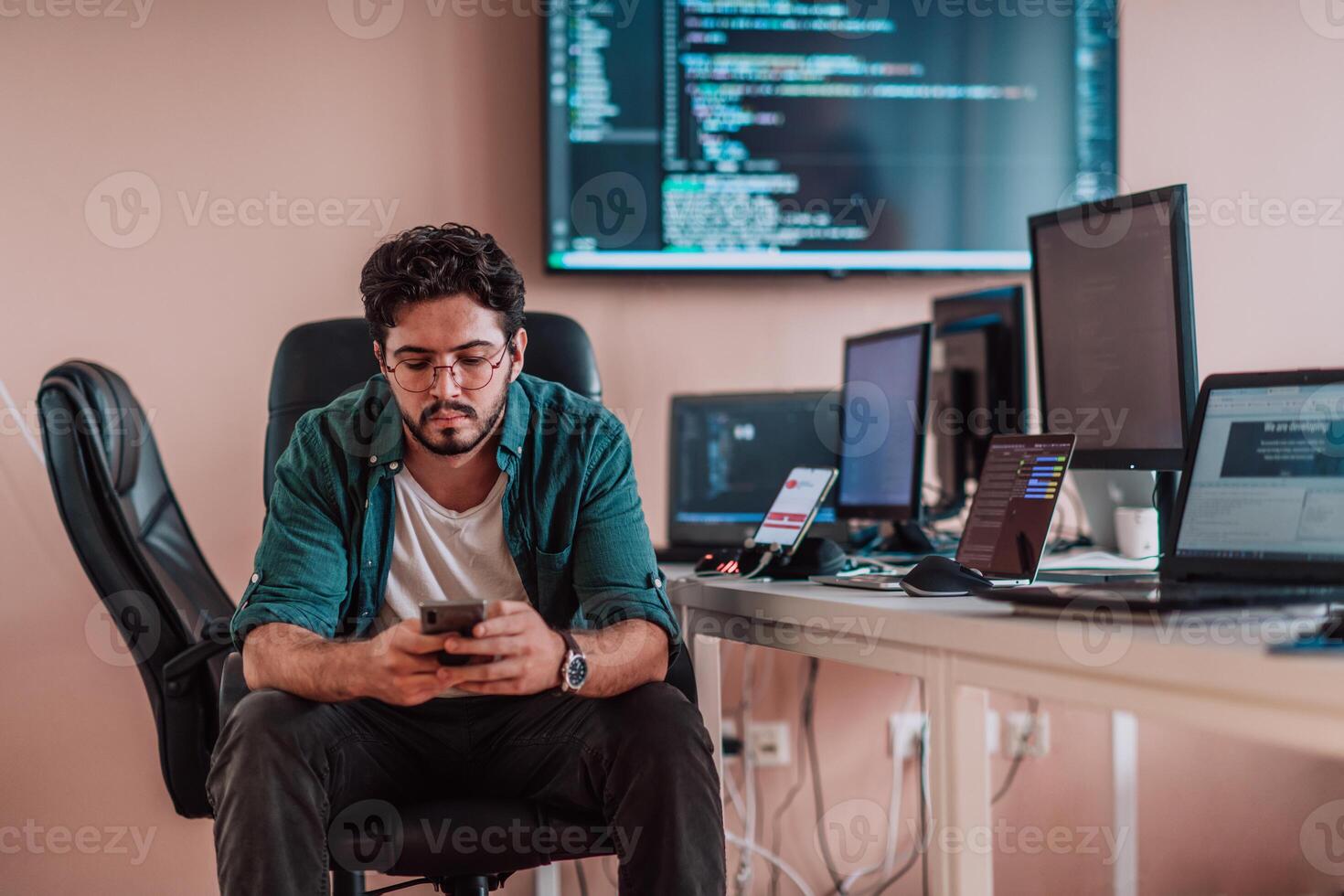 A programmer diligently testing smartphone applications while sitting in their office. photo