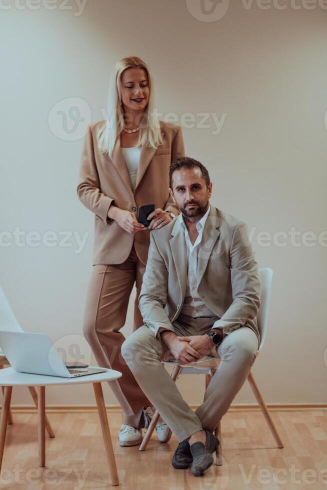 A business couple posing for a photograph together against a beige backdrop, capturing their professional partnership and creating a timeless image of unity and success. photo