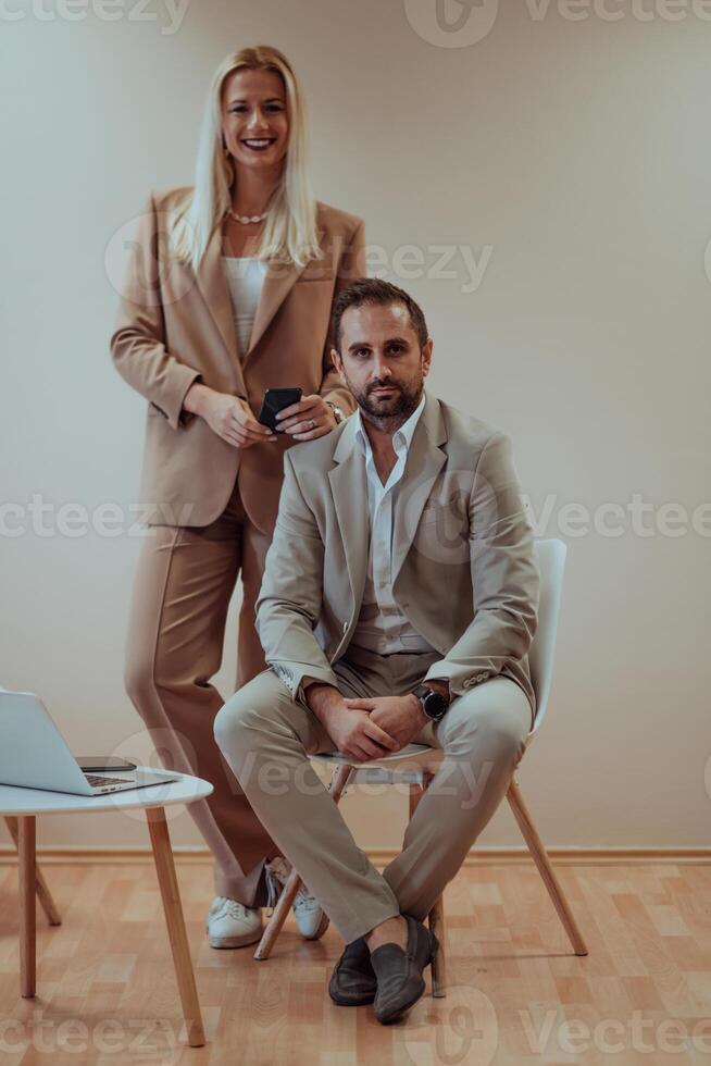 A business couple posing for a photograph together against a beige backdrop, capturing their professional partnership and creating a timeless image of unity and success. photo