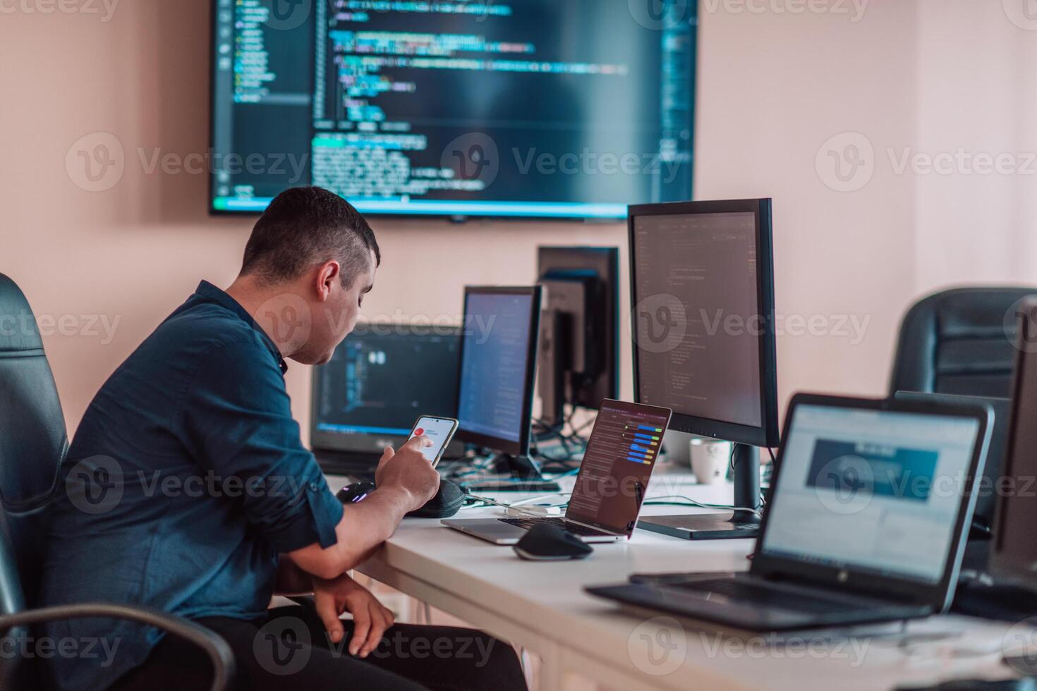 A programmer diligently testing smartphone applications while sitting in their office. photo