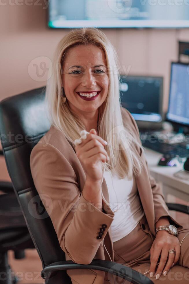 A businesswoman sitting in a programmer's office surrounded by computers, showing her expertise and dedication to technology. photo