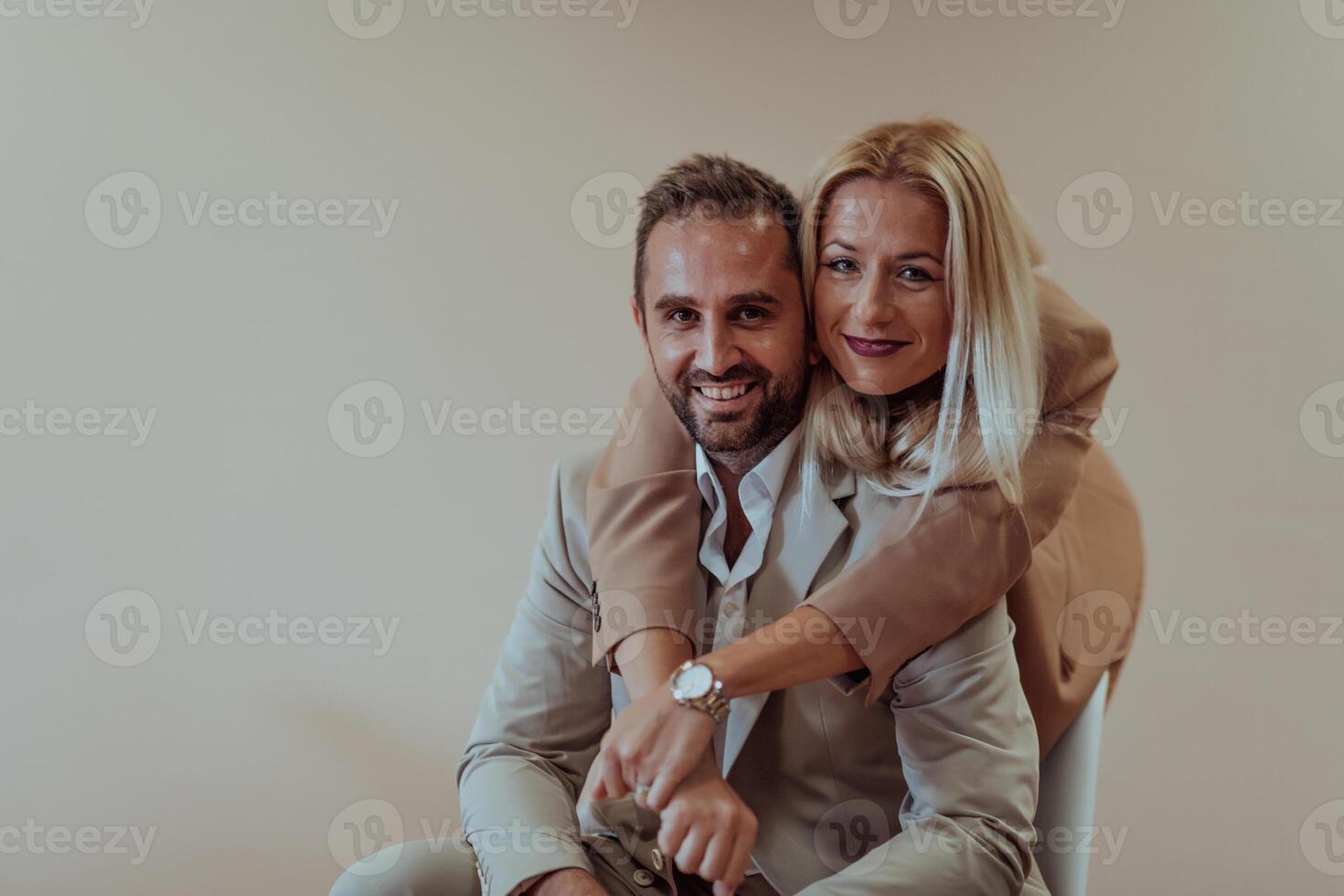 A business couple posing for a photograph together against a beige backdrop, capturing their professional partnership and creating a timeless image of unity and success. photo