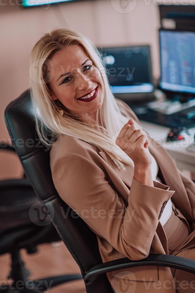 A businesswoman sitting in a programmer's office surrounded by computers, showing her expertise and dedication to technology. photo