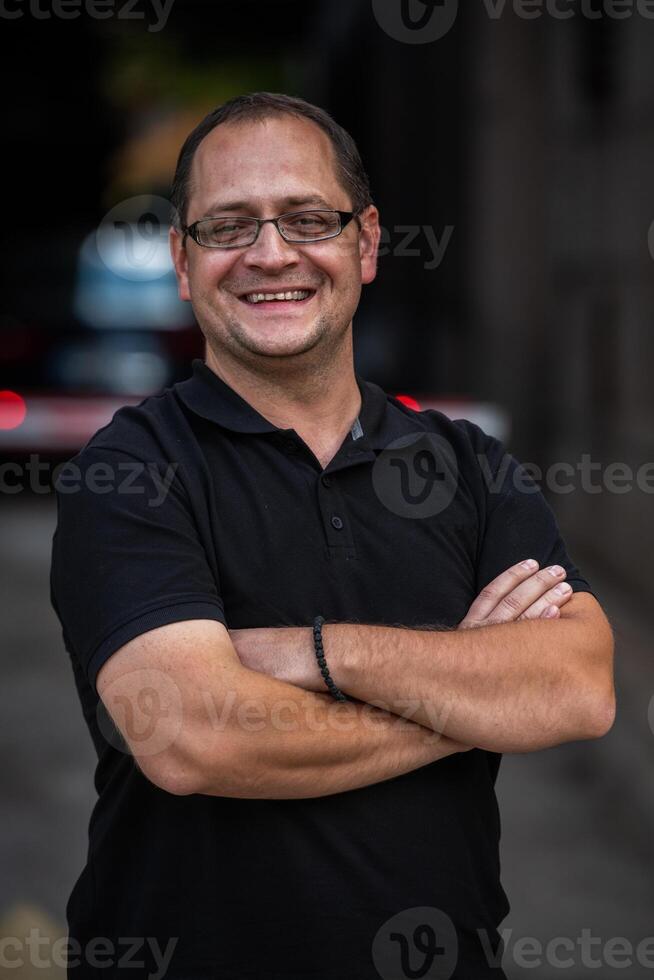 A successful businessman with crossed arms, posing outdoors photo