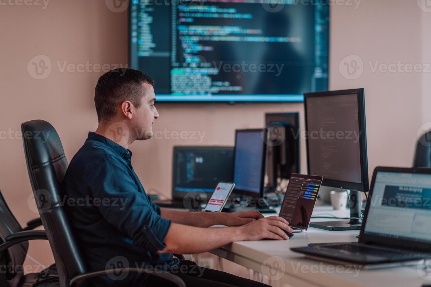 A programmer diligently testing smartphone applications while sitting in their office. photo