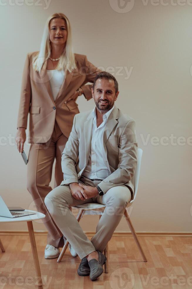A business couple posing for a photograph together against a beige backdrop, capturing their professional partnership and creating a timeless image of unity and success. photo