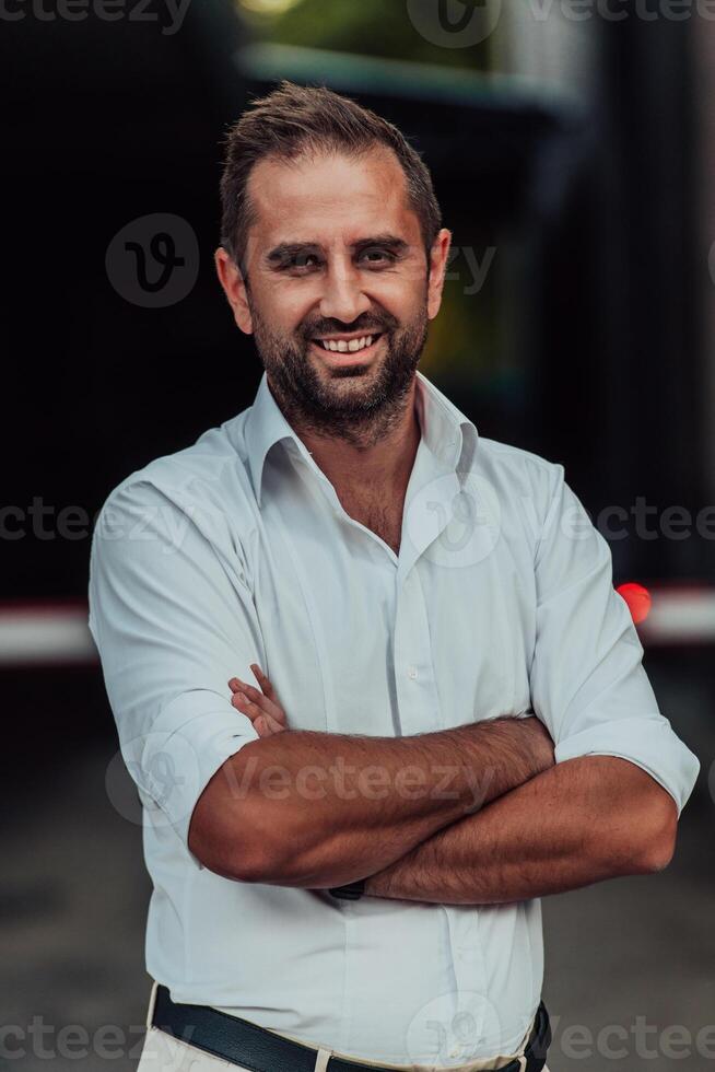 A successful businessman in a white shirt with crossed arms posing outdoors photo