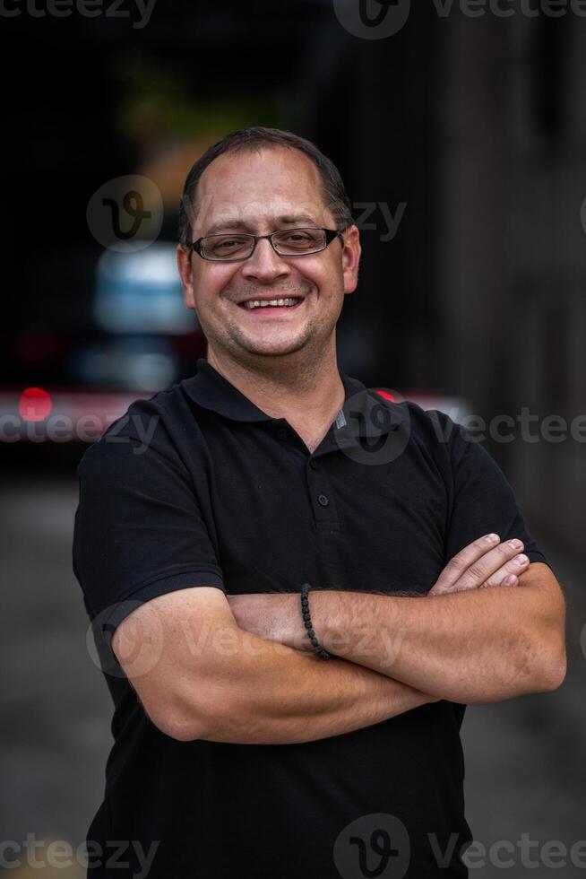 A successful businessman with crossed arms, posing outdoors photo