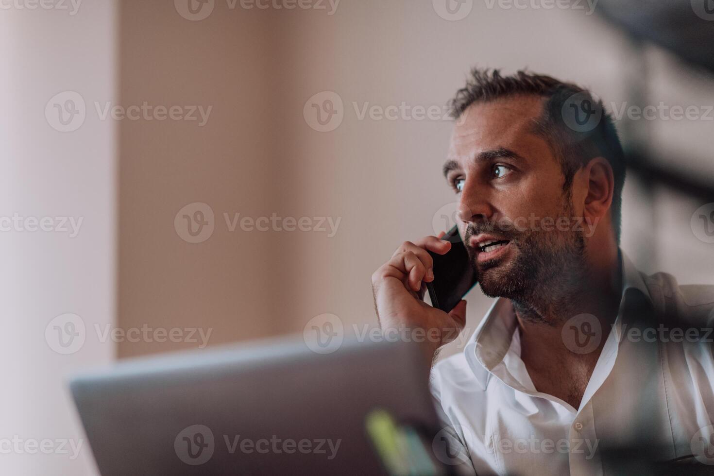 A businessman talking on his smartphone while seated in an office, showcasing his professional demeanor and active communication. photo