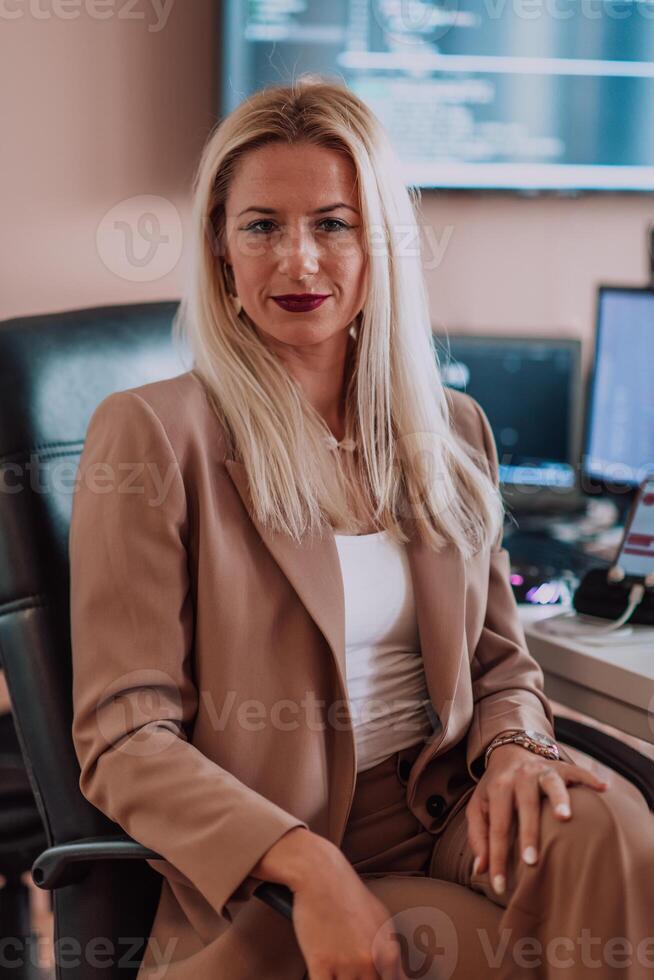 A businesswoman sitting in a programmer's office surrounded by computers, showing her expertise and dedication to technology. photo
