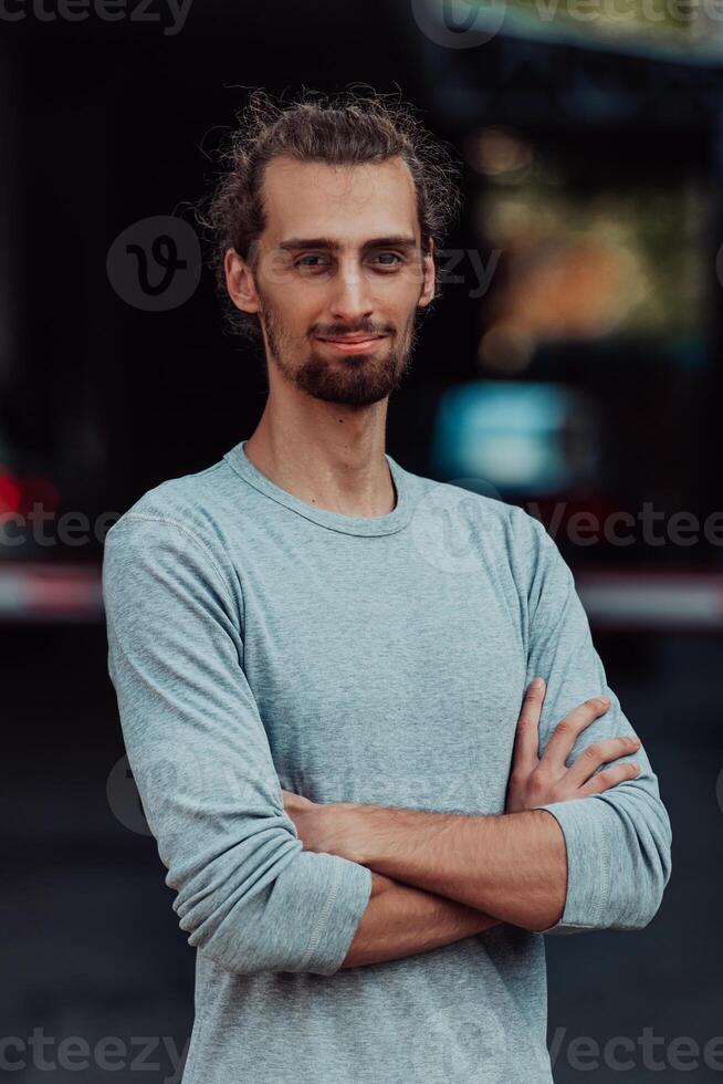 Portrait of a young successful businessman with crossed arms in front of the company photo