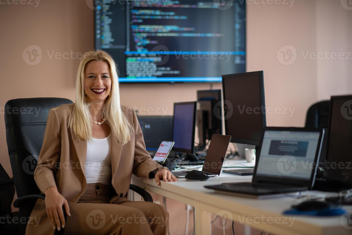 A businesswoman sitting in a programmer's office surrounded by computers photo