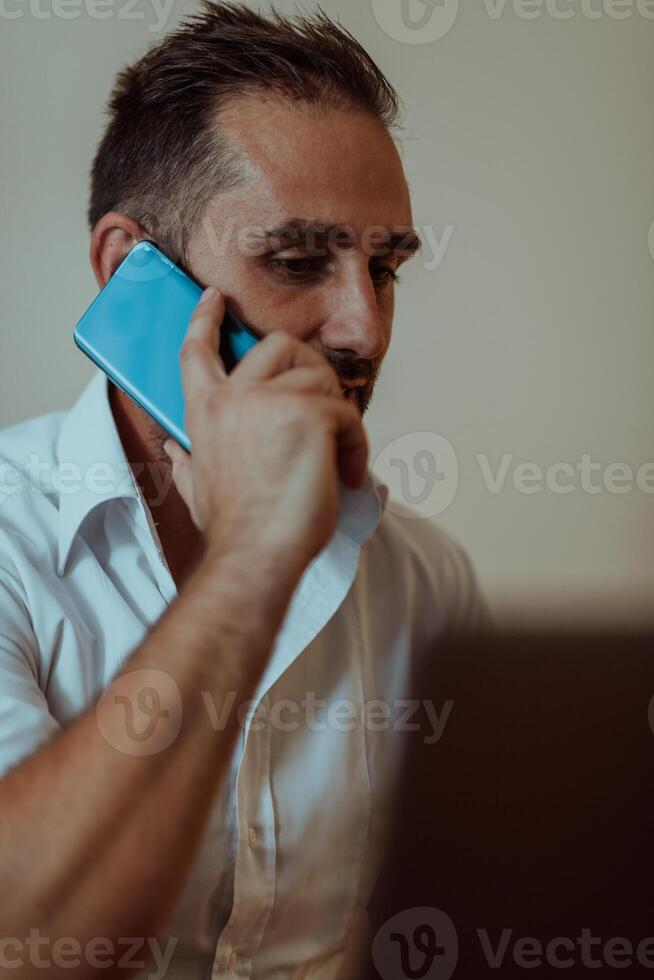 A businessman talking on his smartphone while seated in an office, showcasing his professional demeanor and active communication. photo