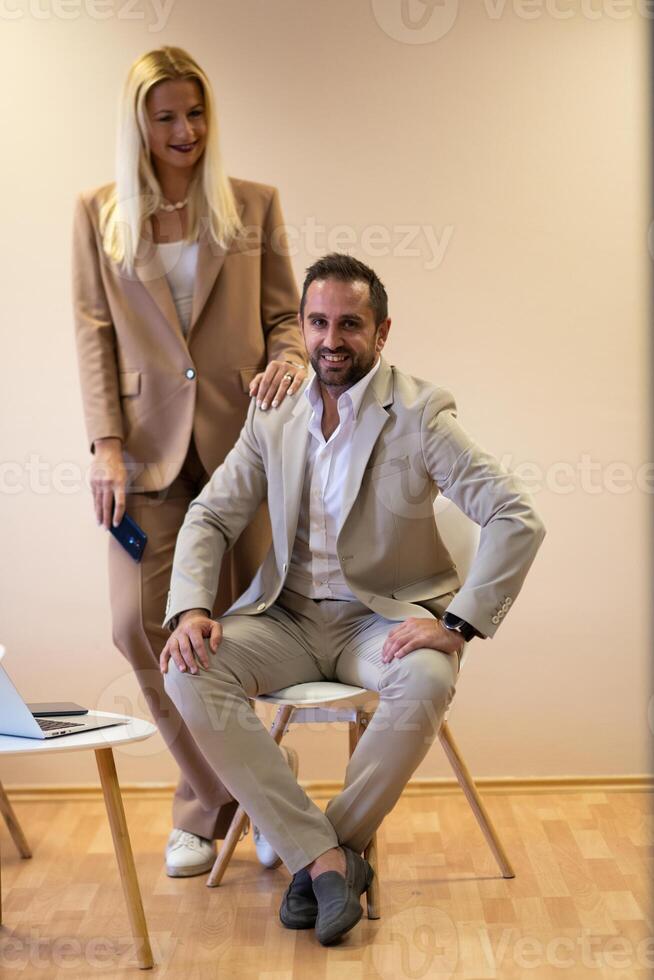 A business couple posing for a photograph together against a beige backdrop, capturing their professional partnership and creating a timeless image of unity and success. photo