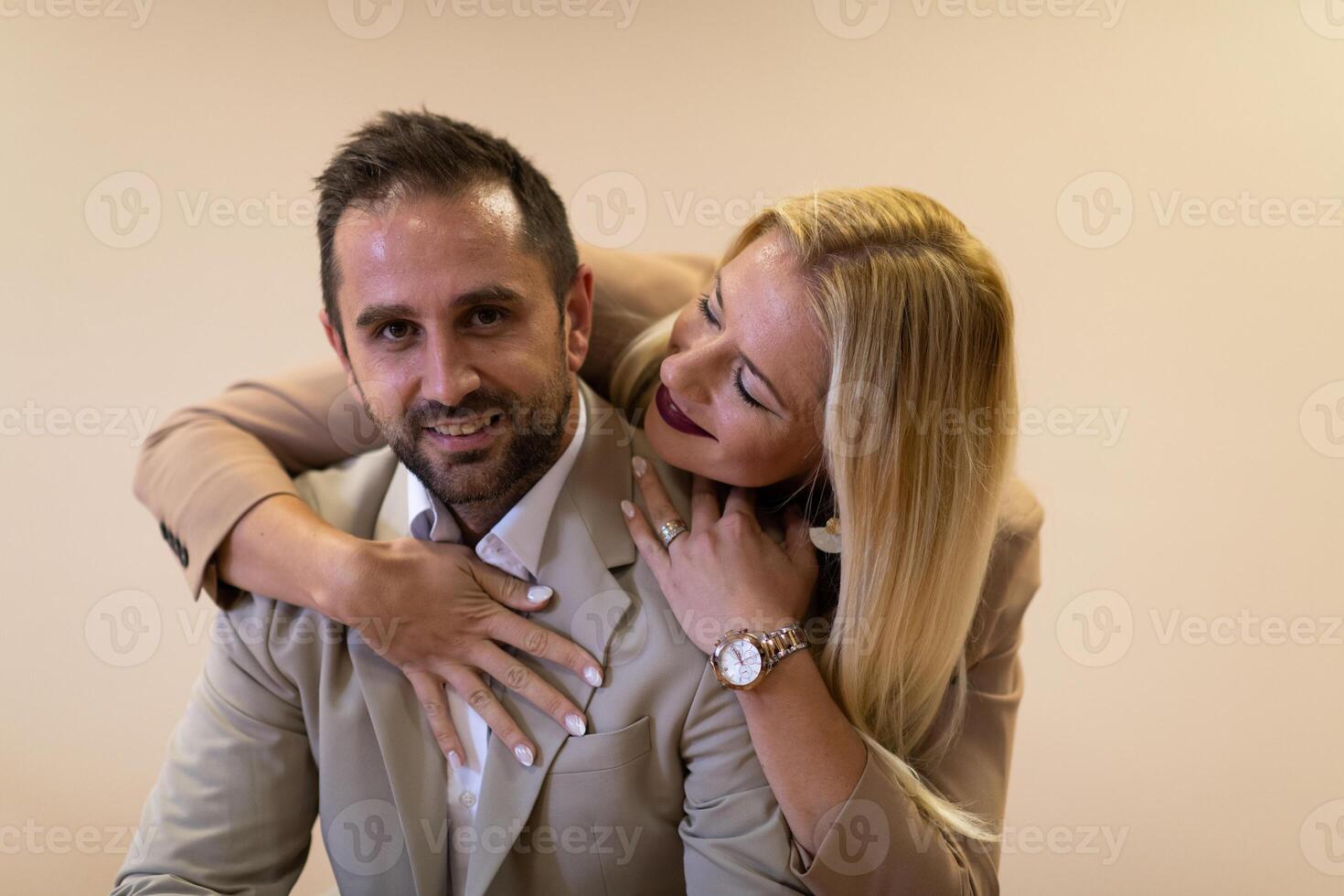 A business couple posing for a photograph together against a beige backdrop, capturing their professional partnership and creating a timeless image of unity and success. photo